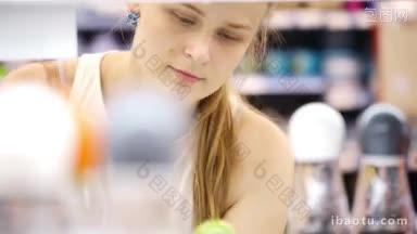 年轻的金发女子仔细分析产品在商店的观点通过产品